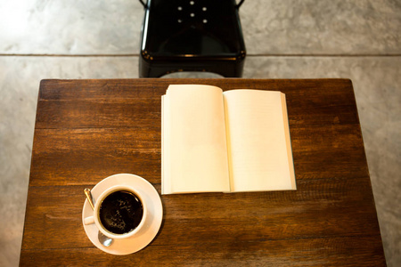 一杯咖啡在木桌上打开书和黑金属茶