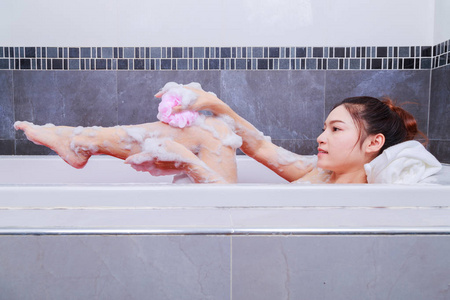 浴室的浴缸里的女人用海绵洗腿