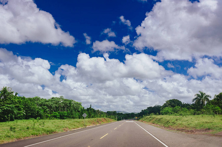 公路穿越森林和多云的丘陵背景