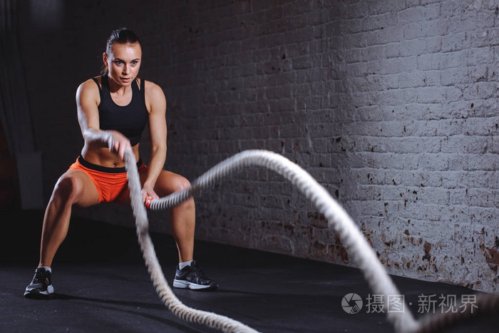 这位女士让与战斗绳子在功能训练健身房锻炼