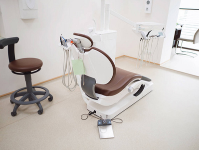 现代牙科诊所。白色医疗灯中牙医用的棕色真皮椅和其他配件