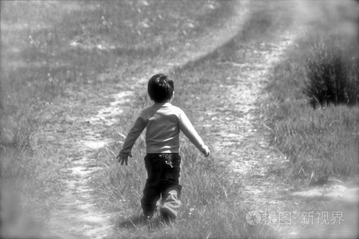在一个阳光明媚的日子里, 一个小男孩, 在一片青草的草地上奔跑