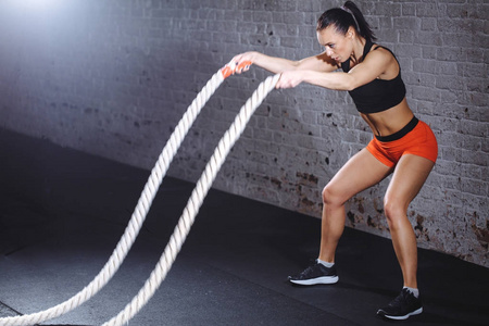 运动妇女做战斗绳索锻炼在健身房