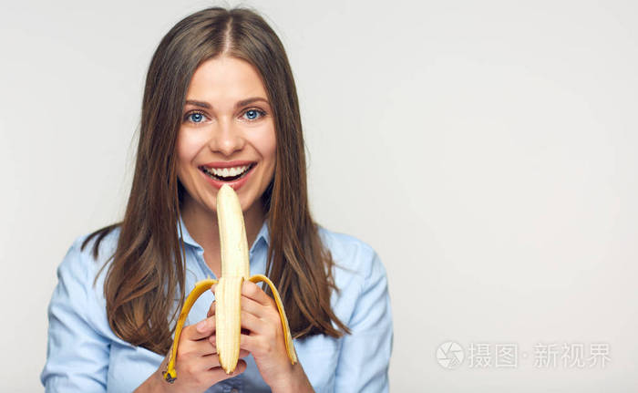微笑的妇女吃香蕉在轻的背景