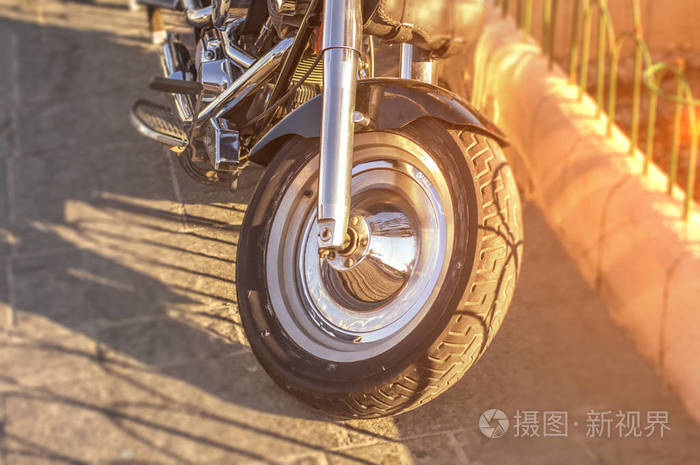 摩托车第一轮停放在城市街道上燃烧的太阳