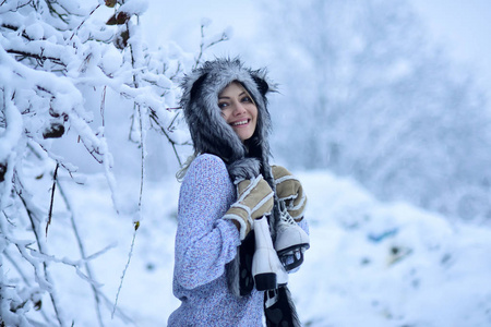 愉快的妇女微笑与图冰鞋在树在雪