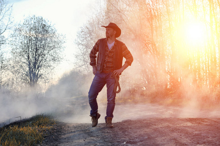 一个男人在田里戴着一顶牛仔帽和一 loso。美国