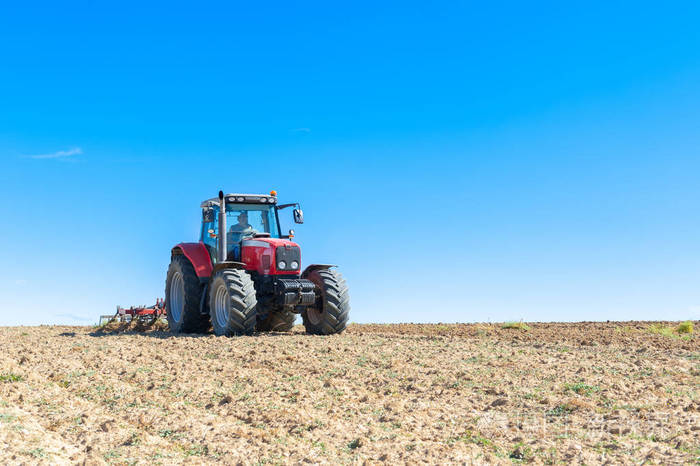 农业拖拉机在蓝色天空背景与前景