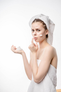 惊讶的年轻女孩用白色的毛巾在她的头上用泡沫清洗脸