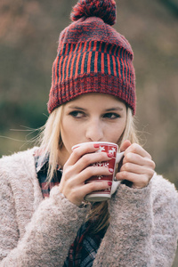女孩在户外喝热饮。杯咖啡或饮料