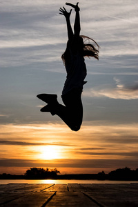 在日落前的湖面上跳跃的女子剪影