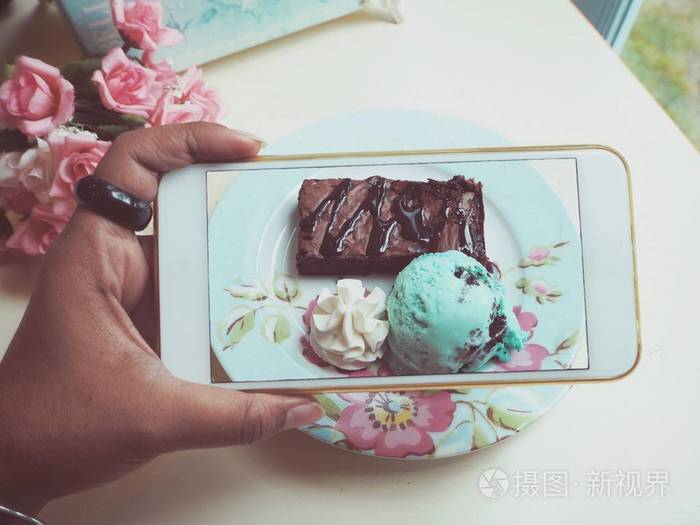 用智能手机在老式盘子上拍冰淇淋薄荷照片
