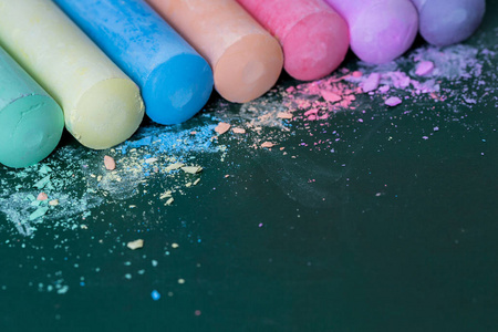 五彩蜡笔, 粉彩。绿色, 黄色, 粉红色, 紫色, 蓝色。彩绘粉彩。把粉笔洒在绿色的木板上