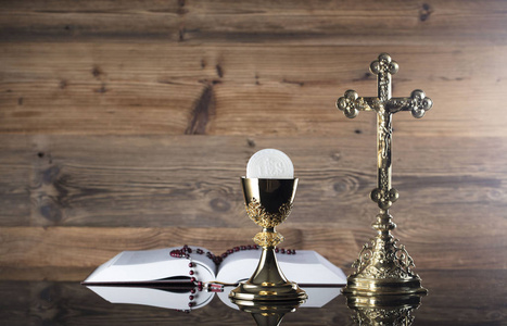 天主教宗教的主题。十字架, 圣洁圣经, 念珠和金黄圣杯在木背景