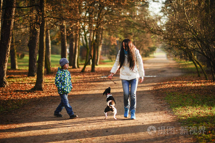 母亲和儿子在秋季公园遛宠物