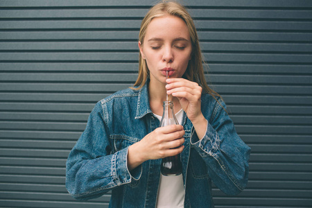 饮料, 人和生活方式概念接近快乐的女人喝可乐与稻草附近的灰墙