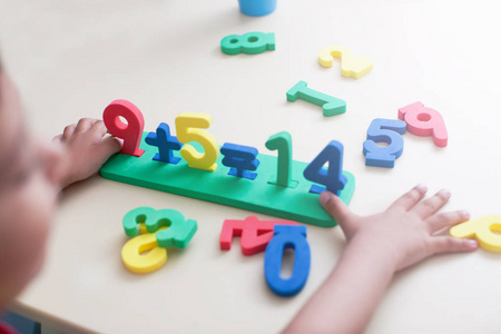 小男孩的特写镜头在白色桌面背景上玩着五颜六色的数字