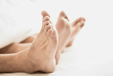 赤脚的情侣在卧室的毯子下。假期和性的幸福。情人节主题