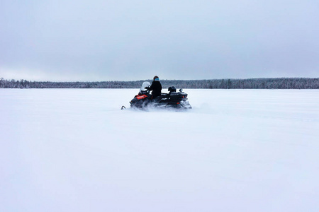 罗瓦涅米芬兰冬季在冰冻湖面驾驶雪地摩托的妇女
