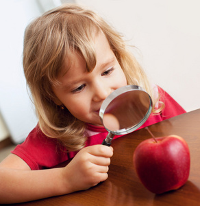 小孩正在考虑放大镜苹果