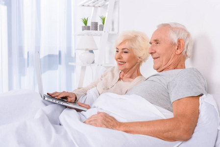 年长夫妇在家里休息时使用手提电脑
