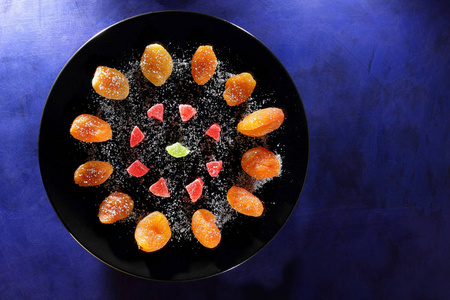 干杏子, 糖的蜜糖水果在深蓝色背景的黑色盘子里