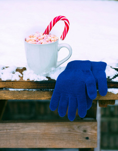 在白雪覆盖的餐桌上用热巧克力和棉花糖杯