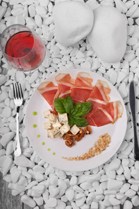 奶酪, 生 hamon, 罗勒, 坚果和一杯红酒在透明玻璃上的白色石头和木背景, 顶部的看法。昂贵的食物。商务晚餐小吃