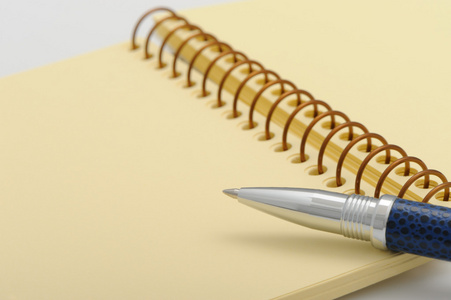 一支钢笔和一本笔记本，上面有一张黄色的纸