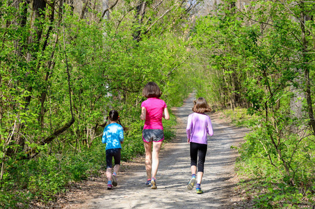 家庭健身和体育 快乐积极的母亲和孩子们在户外慢跑，在森林中运行