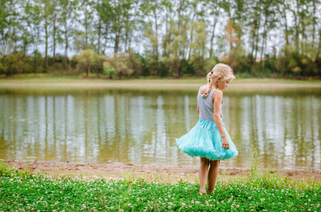 小孩子在蓝色的礼服独自在绿色的性质在草地旁边的河流