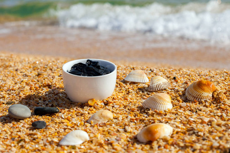 在海滩上的一杯水疗的死海泥