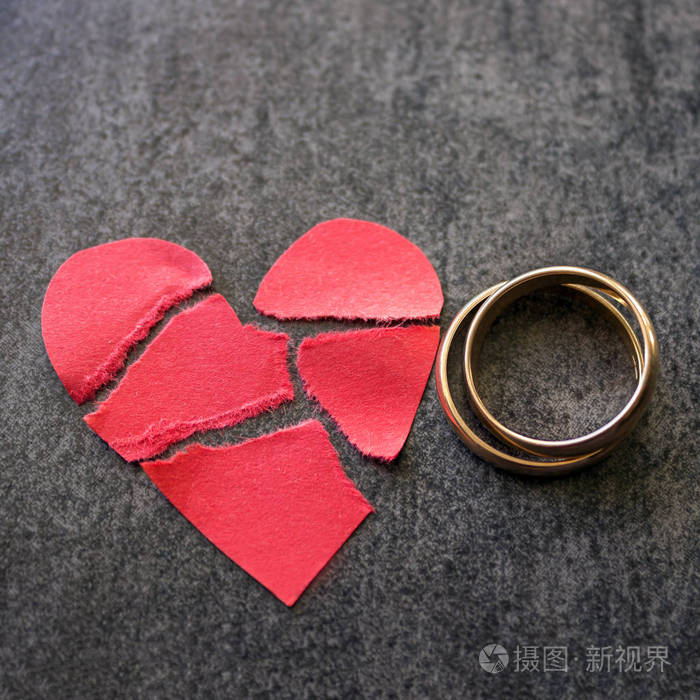 结婚戒指和破碎的红色心黑色的背景让步