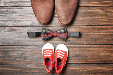 弓领带, 大和小鞋子在木背景。父亲节作文