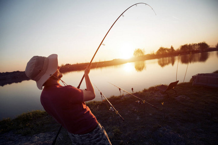 男人在日落钓鱼和放松而享受的业余爱好