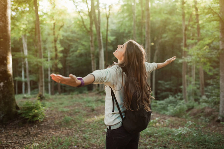 emgracing 的太阳和自然与背包在森林中的夕阳光在秋季季节, 仰望