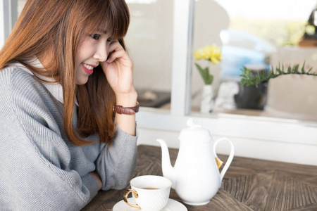 早午餐时, 女人坐在咖啡馆里喝热茶。亚洲女性有