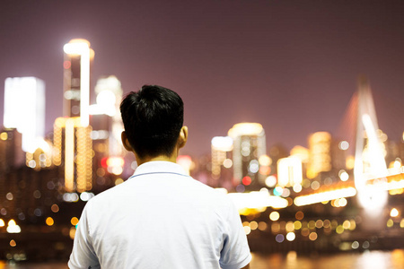 重庆新城区城市夜景的年轻中国男子背光照片