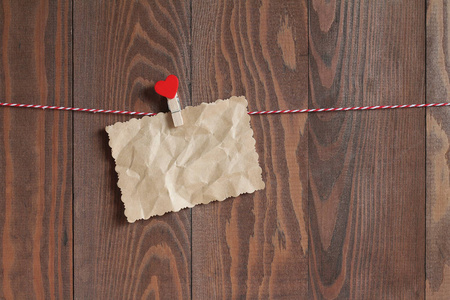 用红心的木 clothespeg 在绳子上的皱巴巴的纸废料