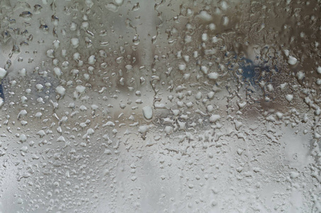 窗玻璃背景下的雨滴和冰冻水
