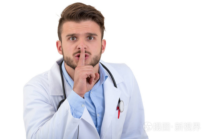 用他的手指捂着嘴孤立的白色背景上的英俊的医生手势沉默