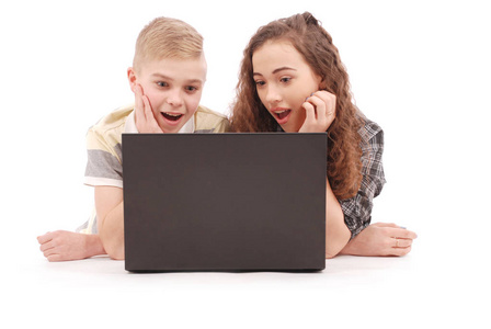 男孩和女孩使用一台笔记本电脑，躺在地板上