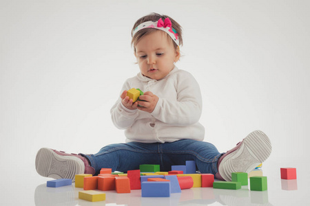 可爱的女婴玩白色背景的木制立方体
