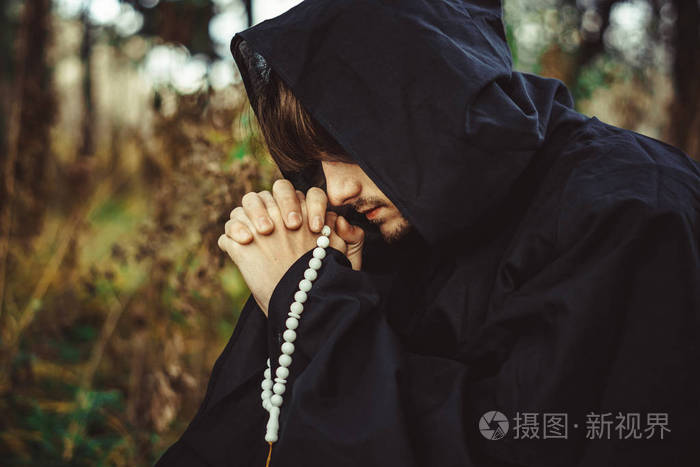 穿着长袍的和尚在树林里祈祷
