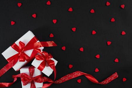 黑色背景的白色礼品盒与红丝带。情人节贺卡
