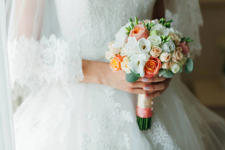 不可识别的新娘是站在窗口附近和控股与白 桃花玫瑰花的婚礼花束。特写