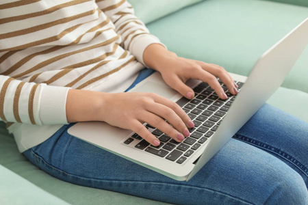 现代笔记本电脑的年轻女子坐在家里的沙发上, 特写