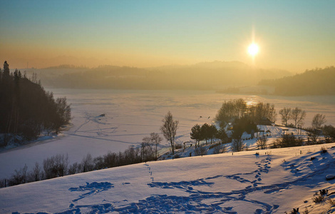 日落时, 白雪覆盖了山上的树木。美丽的冬天