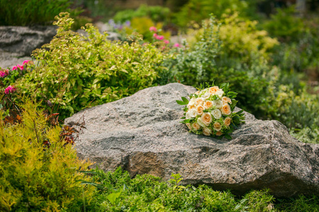 花.美丽的新娘花束躺在石头上。婚礼装饰