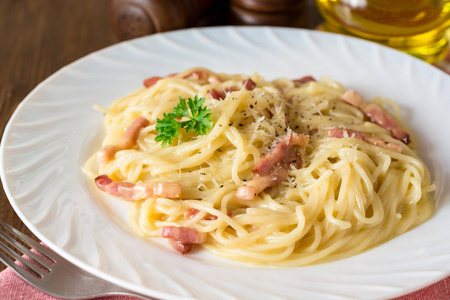 经典的面食 carbonara。意大利面配培根，鸡蛋蛋黄和帕尔玛奶酪在白板上深色木制背景